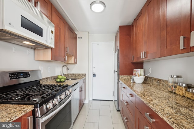 kitchen featuring light stone countertops, appliances with stainless steel finishes, sink, and light tile patterned floors