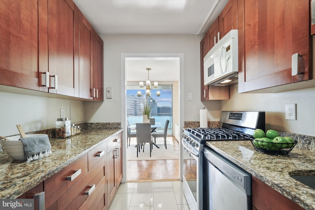 kitchen featuring light tile patterned flooring, appliances with stainless steel finishes, light stone countertops, and an inviting chandelier