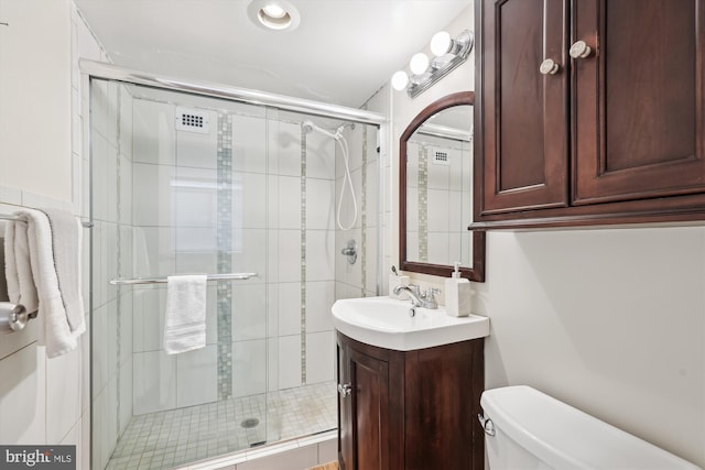 bathroom featuring vanity, toilet, and a shower with door