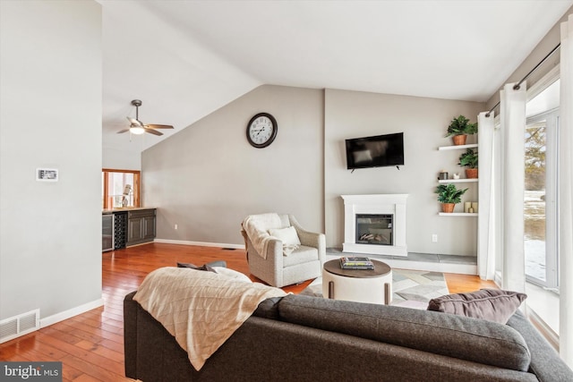 living room with vaulted ceiling, beverage cooler, ceiling fan, and light hardwood / wood-style flooring