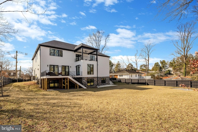 back of property featuring a fenced backyard, a lawn, and stairway