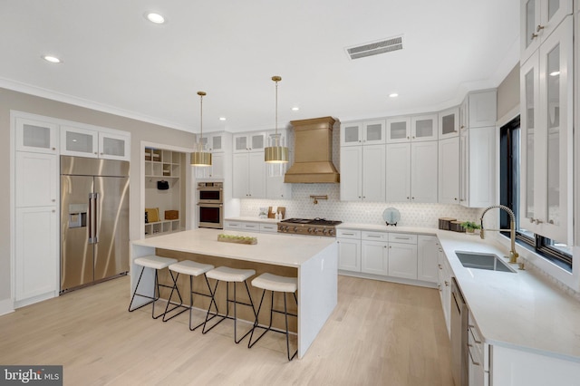 kitchen featuring stainless steel appliances, visible vents, white cabinets, a center island, and custom range hood