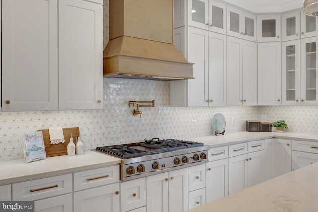 kitchen featuring glass insert cabinets, white cabinetry, and custom exhaust hood