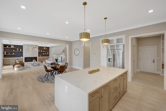 kitchen with high quality fridge, a fireplace, hanging light fixtures, light wood-type flooring, and a center island