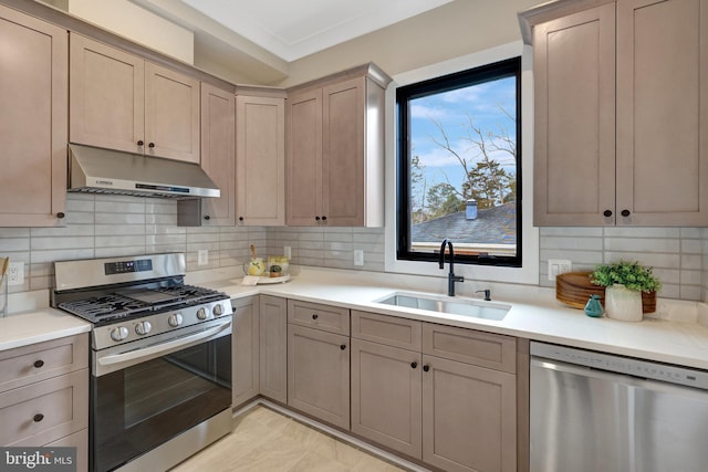 kitchen with under cabinet range hood, stainless steel appliances, a sink, light countertops, and tasteful backsplash