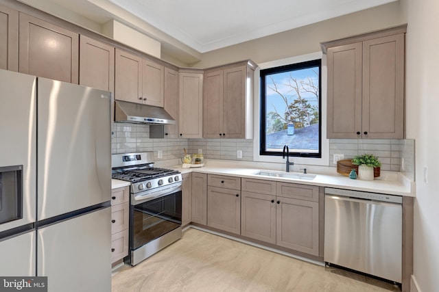 kitchen with decorative backsplash, appliances with stainless steel finishes, light countertops, under cabinet range hood, and a sink