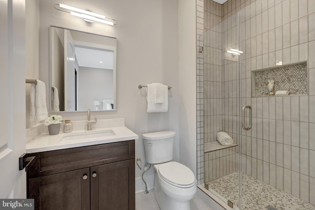 bathroom with vanity, a shower stall, and toilet