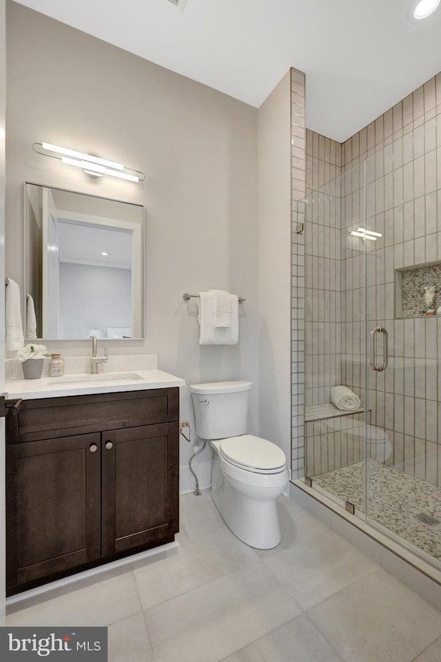 bathroom with tile patterned flooring, toilet, vanity, baseboards, and a shower stall