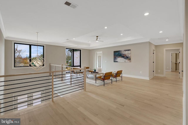 living area featuring recessed lighting, a raised ceiling, visible vents, light wood-style floors, and an upstairs landing