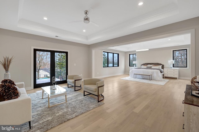 interior space with access to exterior, light wood-style flooring, baseboards, and a raised ceiling