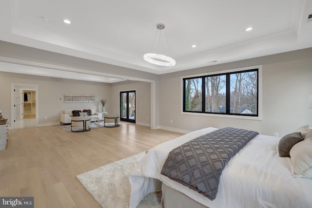 bedroom featuring light wood-type flooring, a raised ceiling, baseboards, and recessed lighting