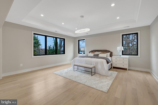 bedroom with visible vents, baseboards, a raised ceiling, light wood-style flooring, and recessed lighting