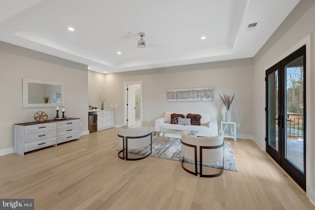 interior space featuring light wood finished floors, visible vents, a tray ceiling, and baseboards