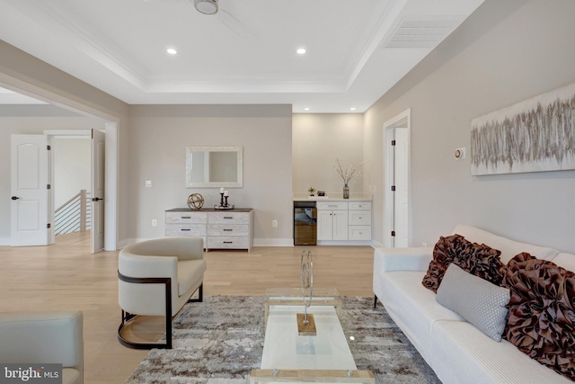 living room with visible vents, baseboards, a raised ceiling, light wood-type flooring, and recessed lighting