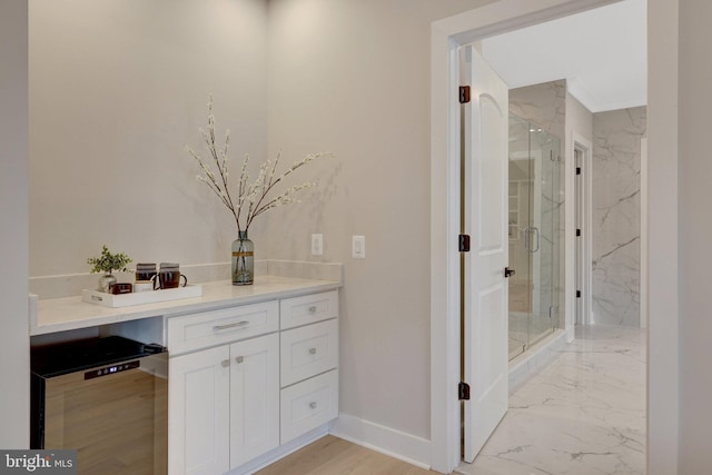 bathroom with marble finish floor, a marble finish shower, baseboards, and vanity