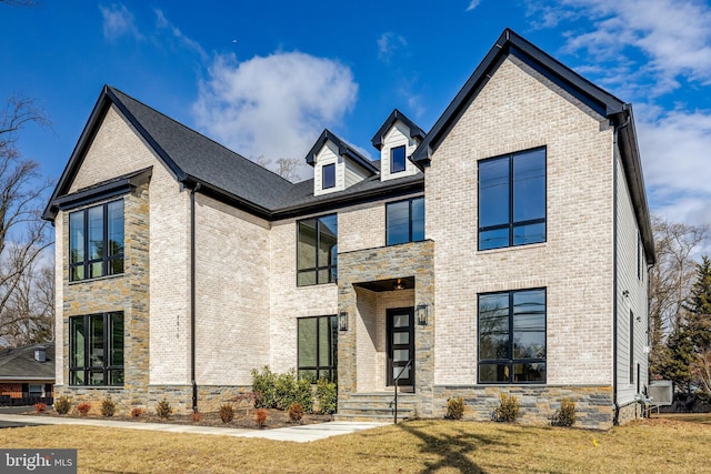 view of front of home with stone siding, a front lawn, and brick siding