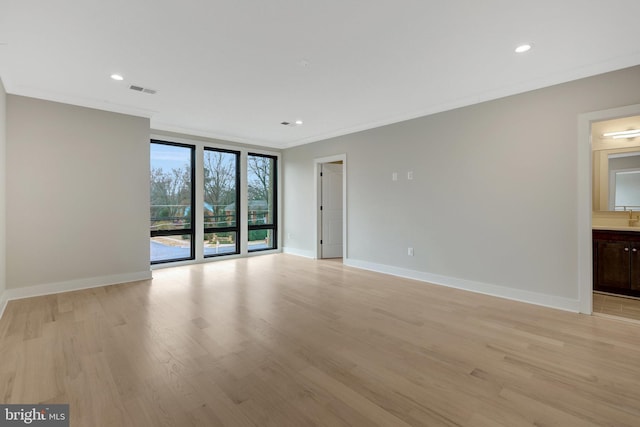 empty room featuring light wood finished floors, baseboards, ornamental molding, and recessed lighting