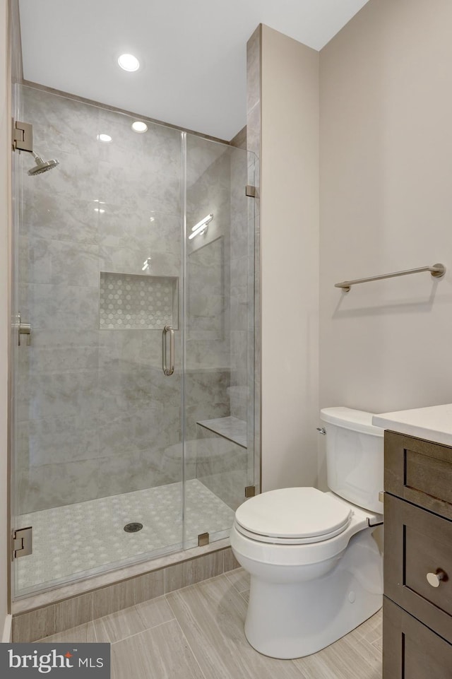 full bath featuring toilet, a shower stall, and vanity