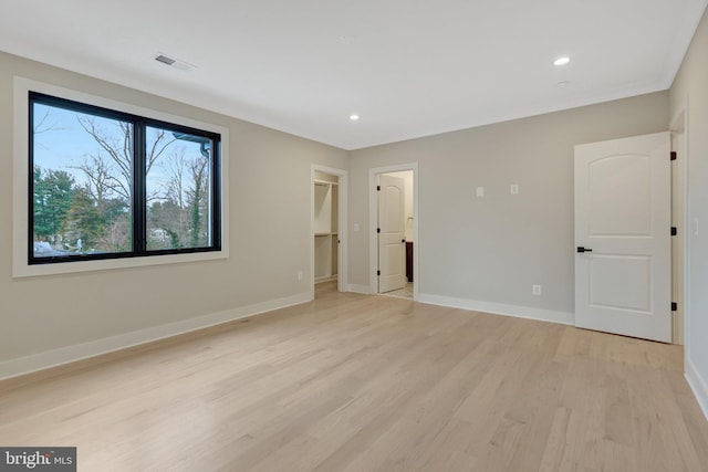 unfurnished bedroom with visible vents, baseboards, light wood-style flooring, a walk in closet, and recessed lighting