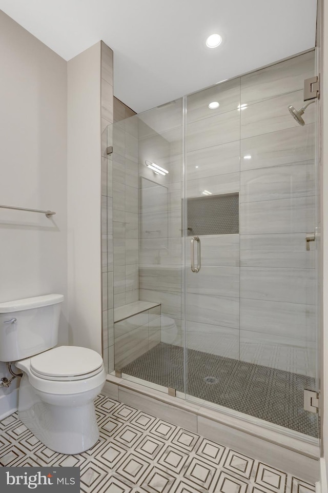 full bath featuring toilet, a stall shower, and tile patterned floors