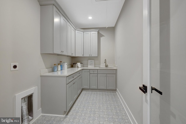 washroom featuring cabinet space, attic access, baseboards, a sink, and electric dryer hookup