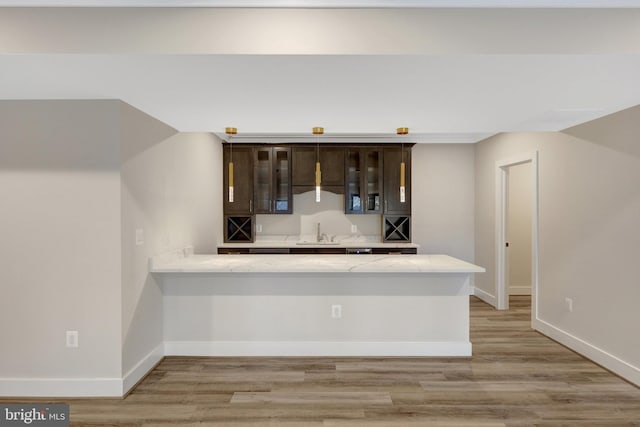 kitchen with a peninsula, glass insert cabinets, light countertops, and dark brown cabinets