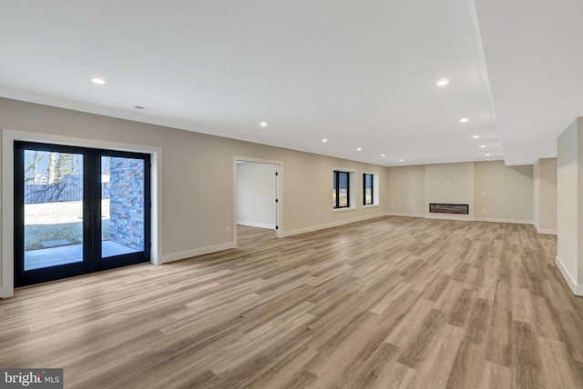 unfurnished living room with light wood-type flooring, recessed lighting, french doors, and baseboards