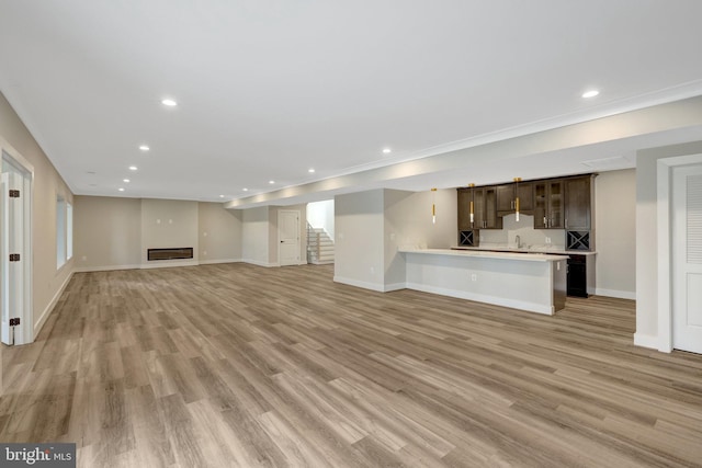 unfurnished living room featuring light wood-style floors, recessed lighting, a glass covered fireplace, and stairway