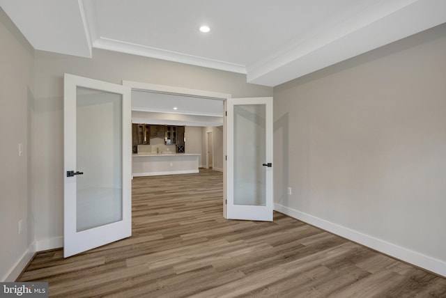 empty room with ornamental molding, french doors, wood finished floors, and baseboards