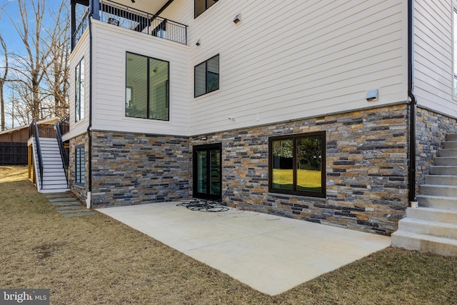 back of house with stone siding, stairs, and a patio