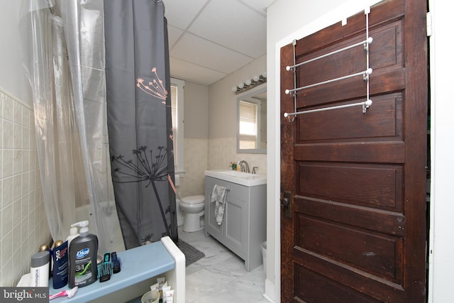 bathroom with vanity, tile walls, a drop ceiling, and toilet