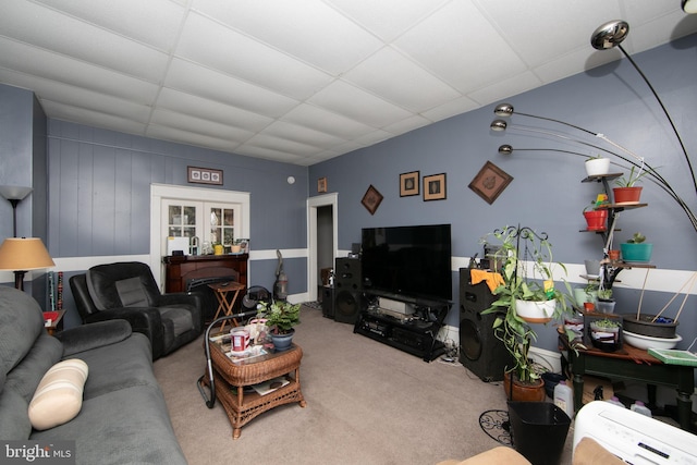 carpeted living room featuring a drop ceiling and french doors