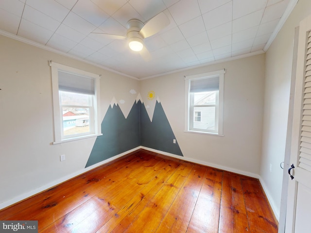 unfurnished room with baseboards, plenty of natural light, wood-type flooring, and crown molding