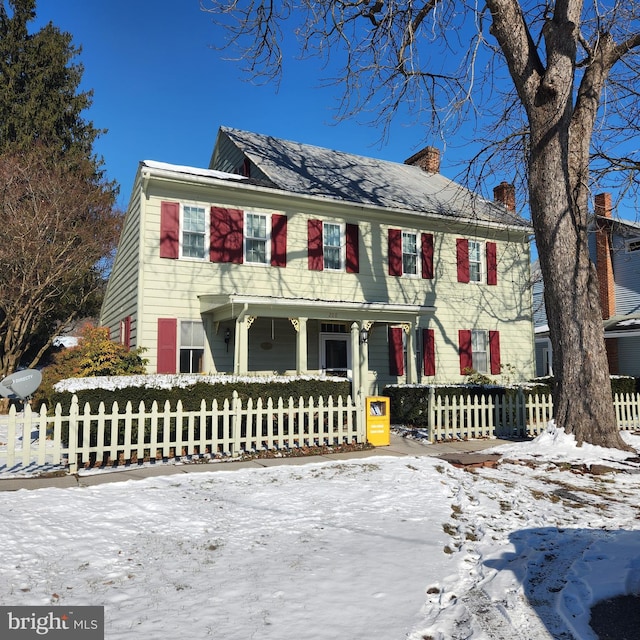 view of front of house with a fenced front yard, a porch, and a chimney