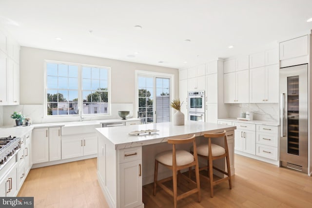 kitchen featuring decorative backsplash, light hardwood / wood-style floors, a center island, and white cabinets