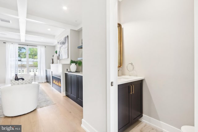 interior space featuring beam ceiling, a bathtub, coffered ceiling, vanity, and wood-type flooring