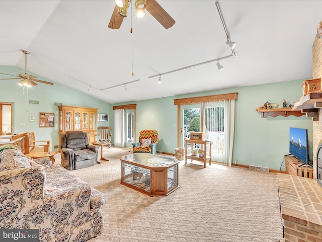 carpeted living room featuring vaulted ceiling, rail lighting, ceiling fan, and a brick fireplace