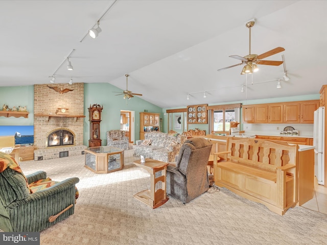 carpeted living room featuring ceiling fan, lofted ceiling, rail lighting, and a brick fireplace