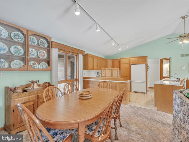 dining area with lofted ceiling, light tile patterned floors, sink, and ceiling fan