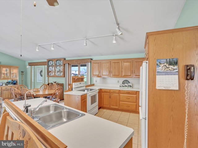 kitchen with sink, white appliances, light tile patterned floors, a kitchen island, and vaulted ceiling