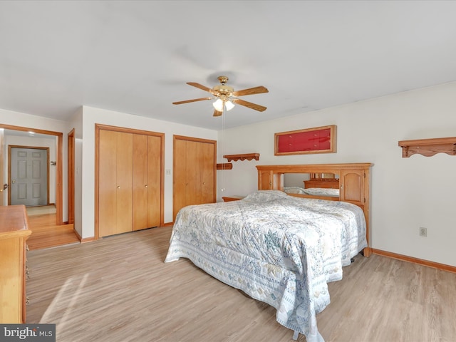 bedroom with ceiling fan, light hardwood / wood-style floors, and two closets