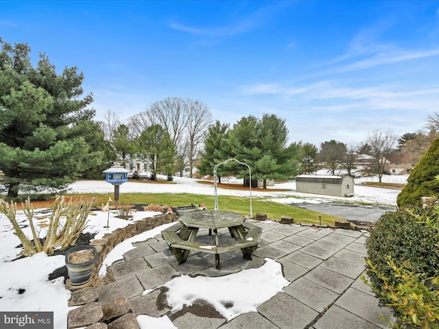 snow covered patio with a storage unit