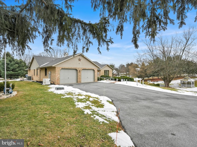 view of front of property featuring a garage, a front yard, and central air condition unit