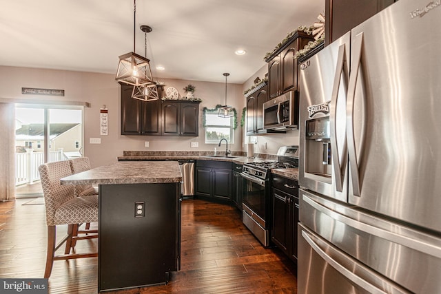 kitchen featuring sink, stainless steel appliances, a kitchen island, dark hardwood / wood-style flooring, and decorative light fixtures