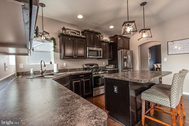 kitchen featuring a breakfast bar, decorative light fixtures, sink, a center island, and stainless steel appliances