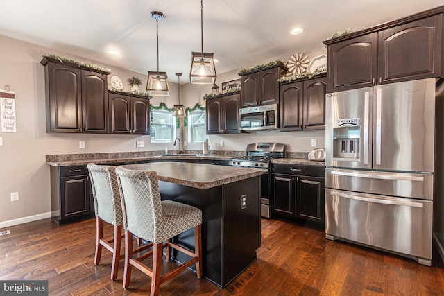 kitchen with a kitchen island, appliances with stainless steel finishes, dark brown cabinetry, and dark hardwood / wood-style flooring