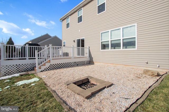 rear view of property featuring a deck and a fire pit