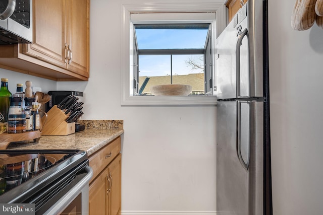 kitchen featuring stainless steel appliances, light brown cabinets, and light stone counters