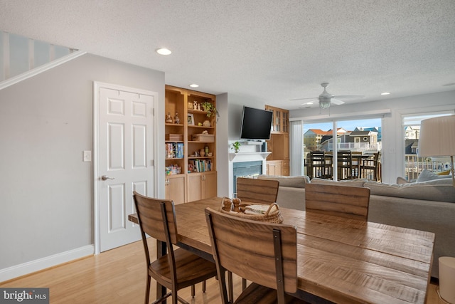 dining space with ceiling fan, a textured ceiling, and light hardwood / wood-style floors