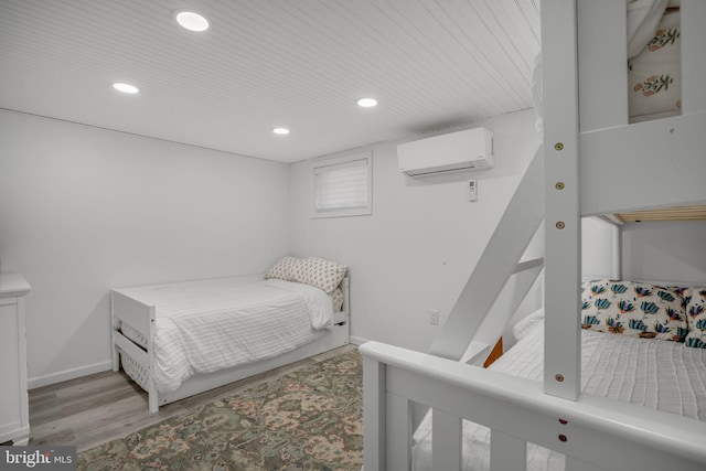 bedroom with light hardwood / wood-style floors and a wall unit AC